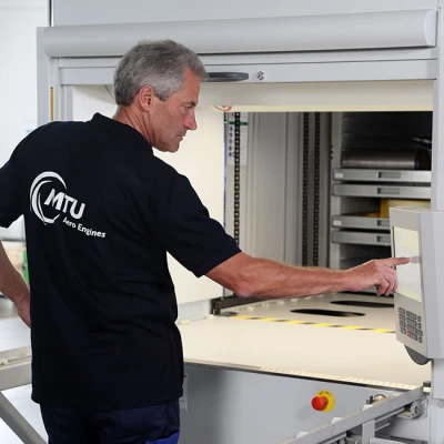 An employee from logistics and scheduling removes measuring equipment from the paternoster rack system.
